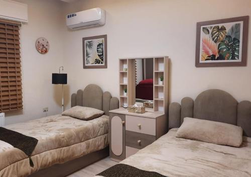 a bedroom with two beds and a mirror at Modern Apartment in Amman in Amman