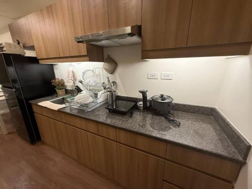 a kitchen with a sink and a black refrigerator at The Camden Place Cozy Family Group Condo Unit in Manila