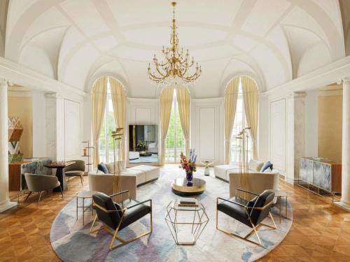a large living room with a chandelier and chairs at Raffles Europejski Warsaw in Warsaw