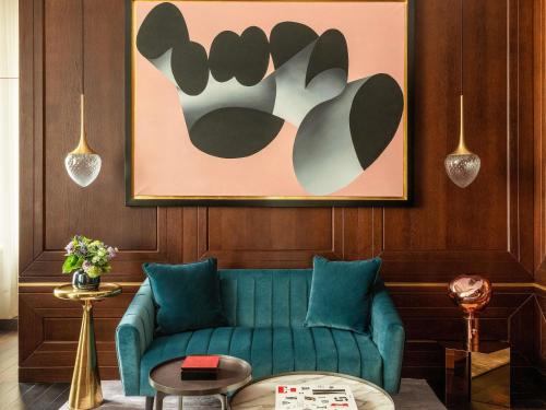 a living room with a green couch and a painting at Raffles Europejski Warsaw in Warsaw