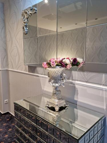 a glass table with a vase with flowers on it at Hotel Gasteiner Hof in Berlin