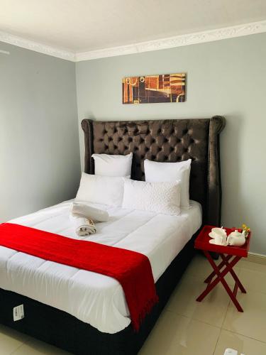 a bedroom with a large bed with a red blanket at LINGAS inn in Richards Bay