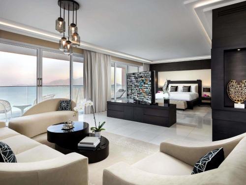ein Wohnzimmer mit einem Bett und ein Zimmer mit einem Sofa in der Unterkunft Fairmont Fujairah Beach Resort in Al Aqah