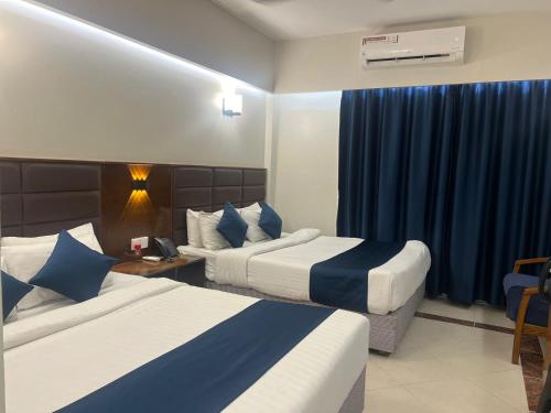 a hotel room with two beds with blue curtains at Hotel Kollol by J&Z Group in Cox's Bazar
