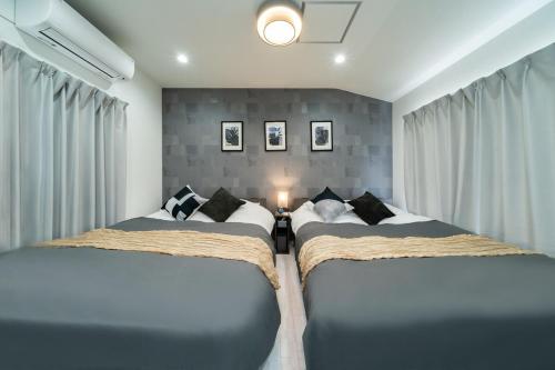 a bedroom with two beds and a wall with curtains at 別邸Zen小岩 Bettei Zen Koiwa in Tokyo