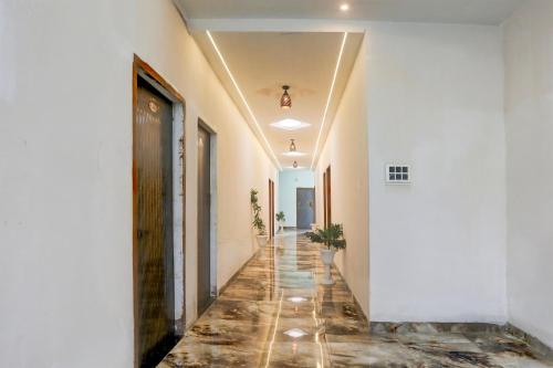 a corridor of a building with white walls and a tile floor at Hotel O MK2 Hotel and Restaurant in Indore