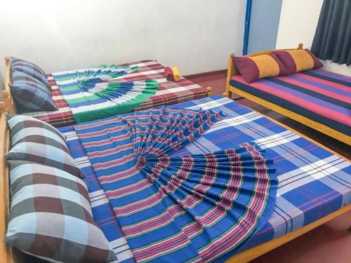 two beds with scarves on them in a room at Hotel Rays Lanka Avissawella in Avissawella