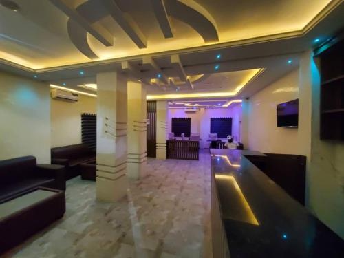 a lobby with couches and a bar with purple lights at Prym Hotel in Owerri