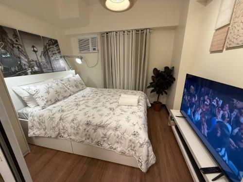 a bedroom with a bed and a flat screen tv at 1BR Luxury Apartment The Camden Place in Manila