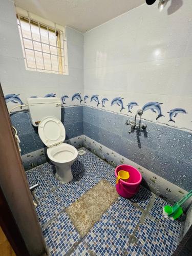 une salle de bain avec toilettes et un sol carrelé bleu dans l'établissement Manikya Homestay, à Malpe