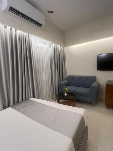 a bedroom with a bed and a blue couch at Hotel Kollol by J&Z Group in Cox's Bazar