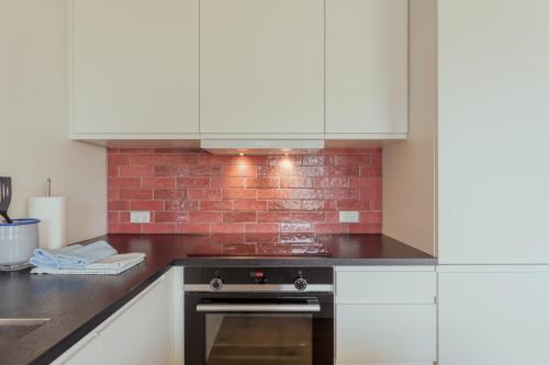 a kitchen with white cabinets and a brick wall at Unwind in Style - 2 BR - Hiking - Family in Tórshavn