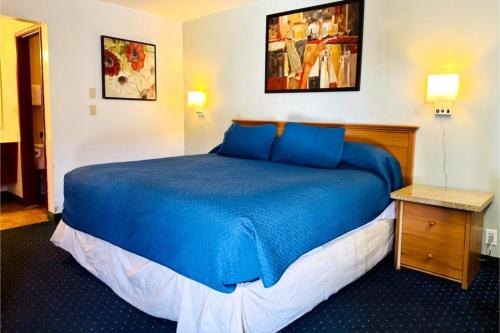 a bedroom with a blue bed in a room at Beaverton Budget Inn in Beaverton