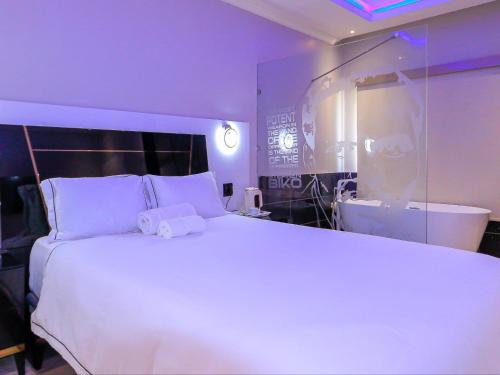 a bedroom with a large white bed and a tub at Skylight Guest Lodge in Johannesburg
