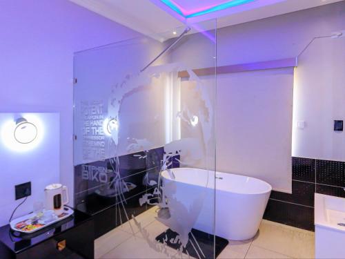 a bathroom with a tub and a glass wall at Skylight Guest Lodge in Johannesburg