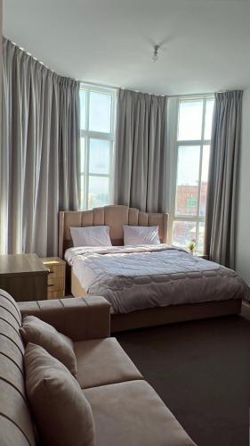 a bedroom with a bed and a couch in front of a window at Khalifa A Home Stay NR in Abu Dhabi