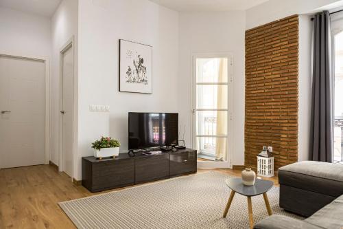 a living room with a television and a brick wall at NOMADIA en LARIOS STREET in Málaga