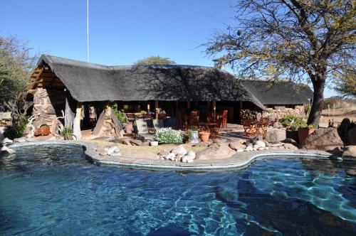 ein Haus mit Tieren, die um einen Swimmingpool herumliegen in der Unterkunft Kalahari Bush Breaks Lodge in Buitepos