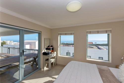 1 dormitorio con cama, ventanas y balcón en Villa Boheme, Panoramic Lagoon Views, 10 Sleeper, en Langebaan