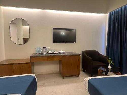 a hotel room with a desk with a tv and a mirror at Hotel Kollol by J&Z Group in Cox's Bazar