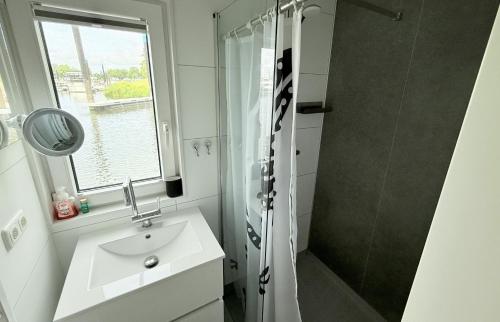 a bathroom with a sink and a shower at Woonboot 1 - Maasterp in Montfort