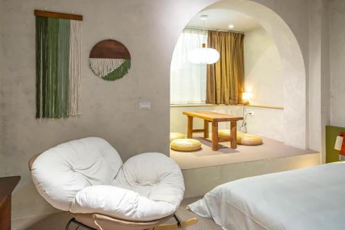 een slaapkamer met een witte stoel en een bed bij Tainan Sunwood B&B in Anping