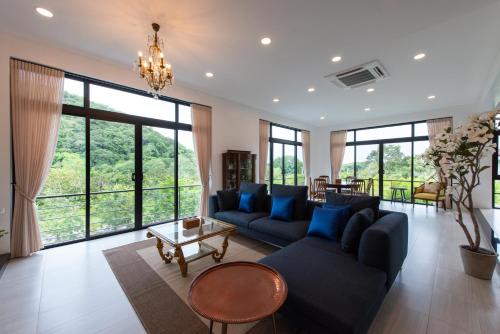 a living room with a blue couch and large windows at Monlada Khaoyai in Mu Si