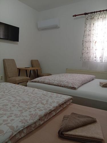 a bedroom with two beds and a chair and a window at Apartman EM-Bajkeraj in Bihać