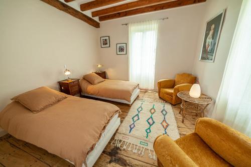a bedroom with two beds and a couch and a chair at Castel La Fabrik'Créative in Saint-Barthélémy-dʼAgenais