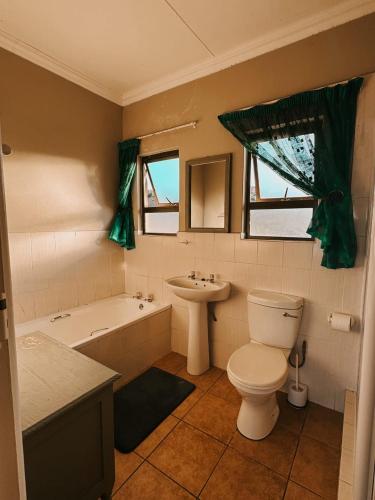 a bathroom with a toilet and a tub and a sink at Wild Bay - Hole in the Wall Resort in Coffee Bay