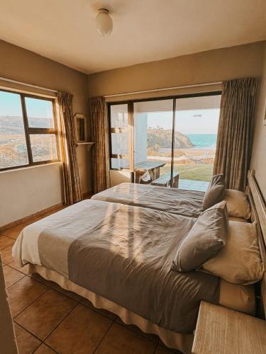 a bedroom with a large bed with a large window at Wild Bay - Hole in the Wall Resort in Coffee Bay