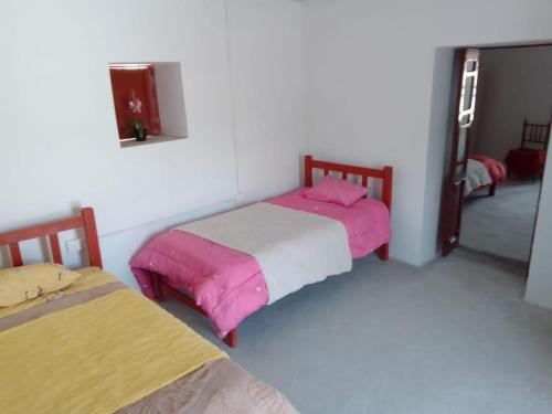a room with two beds with pink and white sheets at Caraz - Cozy Cottage in Caraz