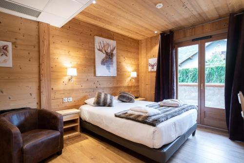 Schlafzimmer mit Holzwänden, einem Bett und einem Stuhl in der Unterkunft La Ferme Du Lac in Thyez
