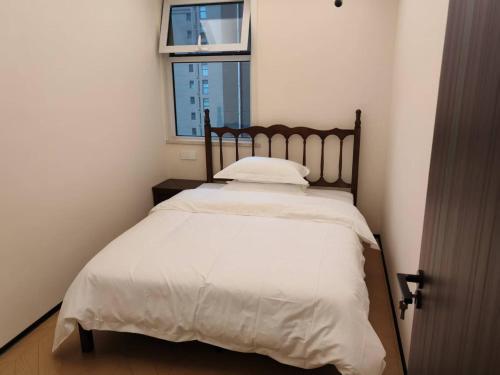 a bedroom with a bed with white sheets and a window at Fenghe Cottage 
