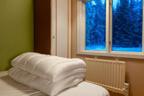 a pile of pillows on a bed in front of a window at The Forest Cabin in Luleå