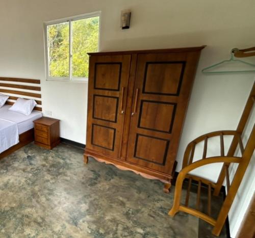 a bedroom with a bed and a cabinet and a chair at Вилла с бассейном и видом на рисовые поля и джунгли in Weligama