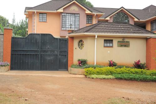 a house with a black fence and a driveway at Davis Court in Nyeri