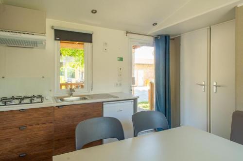 a kitchen with a table and chairs and a sink at Ferienpark Cesenatico Mobilehome Orione für 5 Personen in Zadina Pineta