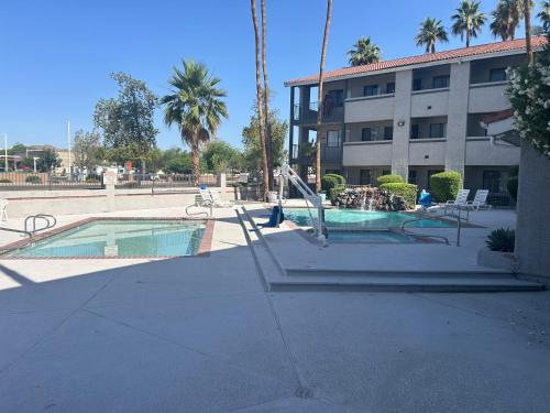 a swimming pool in front of a building with palm trees at Motel 6 Tempe, AZ Elliot Road in Tempe