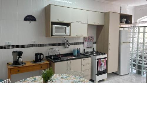 a kitchen with a stove and a refrigerator at Praia do Tombo - Aconchego no Guarujá in Guarujá