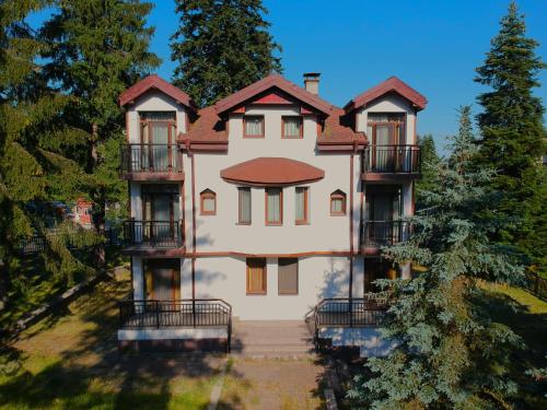 a large house with a staircase leading up to it at Villa Rila Borovets with Hot Pool, Jacuzzi & Sauna by BookVillaBG in Borovets