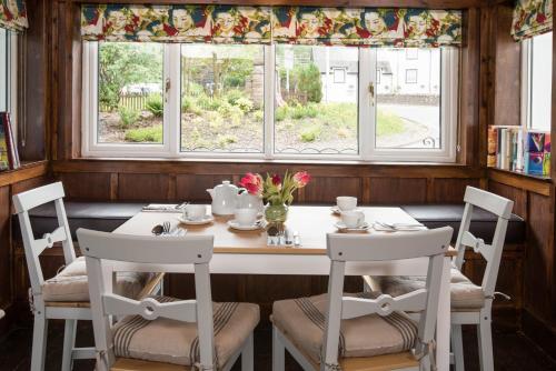 comedor con mesa, sillas y ventana en Glenbruar House, en Crianlarich