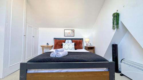 a bedroom with a bed with two towels on it at Lovely 3-Bedroom Maisonette in Hammersmith with rooftop terrace near Shepherds Bush & Ravenscourt Park by Staylio Ltd in London