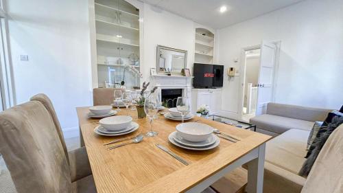 a dining room with a wooden table with wine glasses at Lovely 3-Bedroom Maisonette in Hammersmith with rooftop terrace near Shepherds Bush & Ravenscourt Park by Staylio Ltd in London