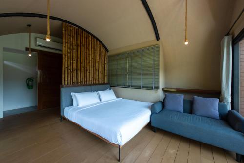 a bedroom with a bed and a blue couch at Monlada Khaoyai in Mu Si