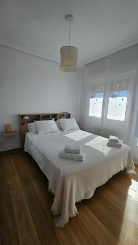 a white bedroom with a large bed with two towels on it at Las Vistillas in San Vicente de la Sonsierra