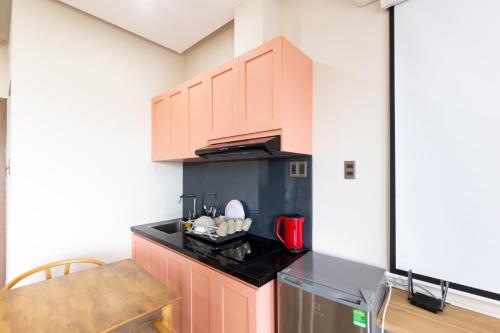 Una cocina con gabinetes rosas y una mesa en una habitación. en SMN Homestay, en Tân Thành (1)