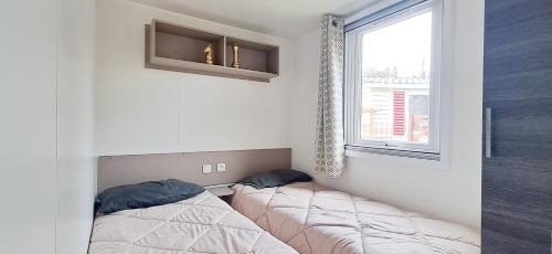 two beds in a room with a window at Naphtase - MH334S - Pins Calmes - Ménage inclus in Saint-Jean-de-Monts