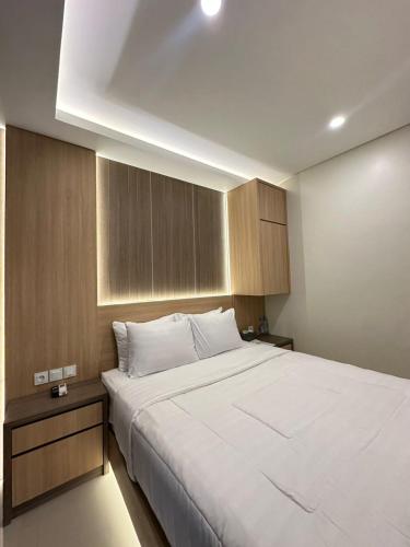 a bedroom with a large white bed and wooden cabinets at The Bali Hotel in Sumedang Utara