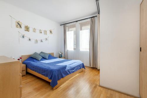 a bedroom with a bed with blue sheets and a window at GRAND ADVENTURE BUDAPEST in Budapest